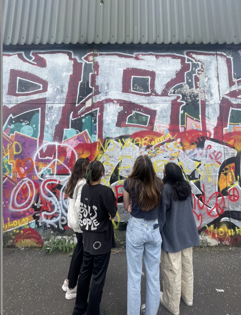 Four students gaze at artwork on peace wall in Belfast. 